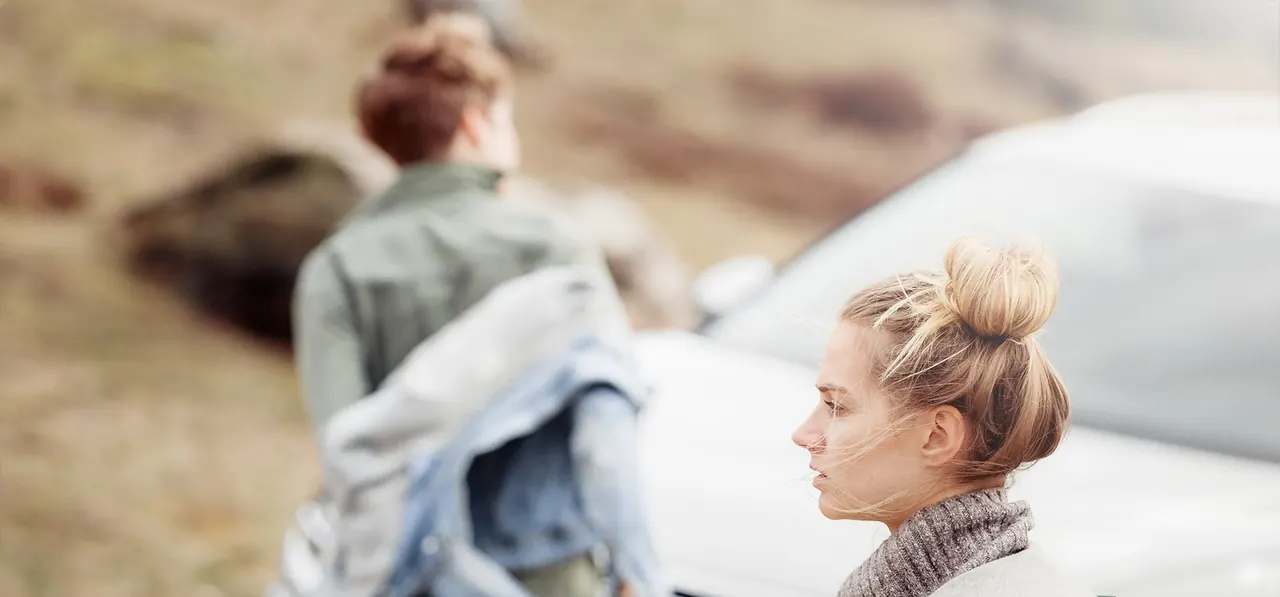 Zwei junge Frauen in Outdoor-Kleidung vor einem Volkswagen in der Natur