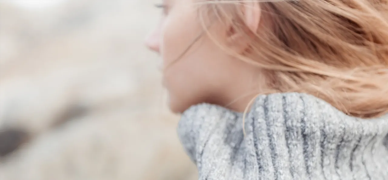 Junge Frau im grauen Strickpullover, Haare im Wind, Volkswagen-Kampagne