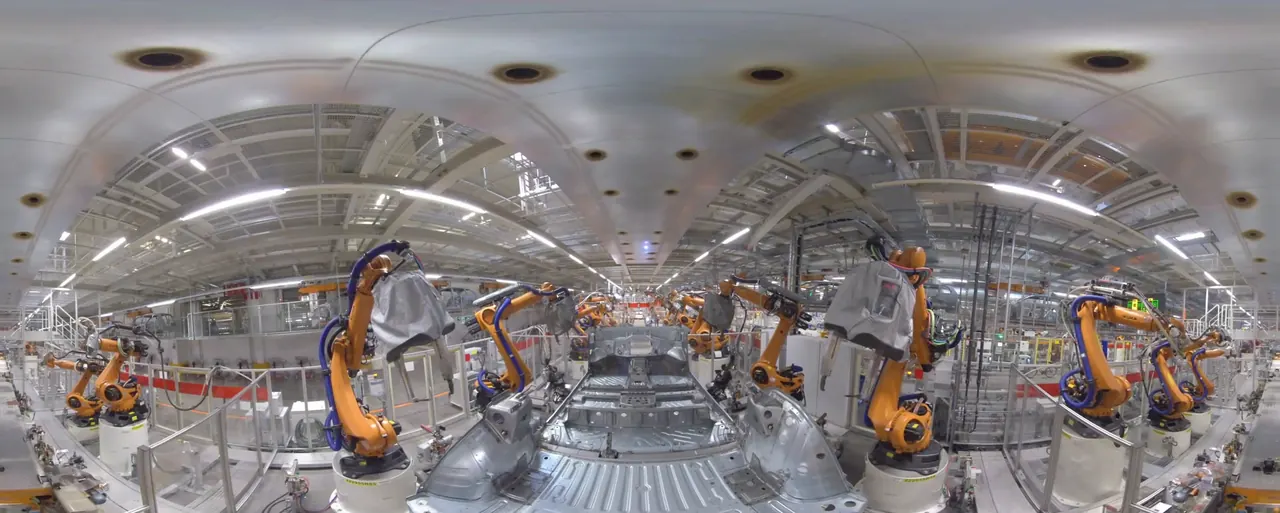 360-Grad-Aufnahme aus der Volkswagen-Produktion mit orangefarbenen Schweißrobotern an einer Karosserie