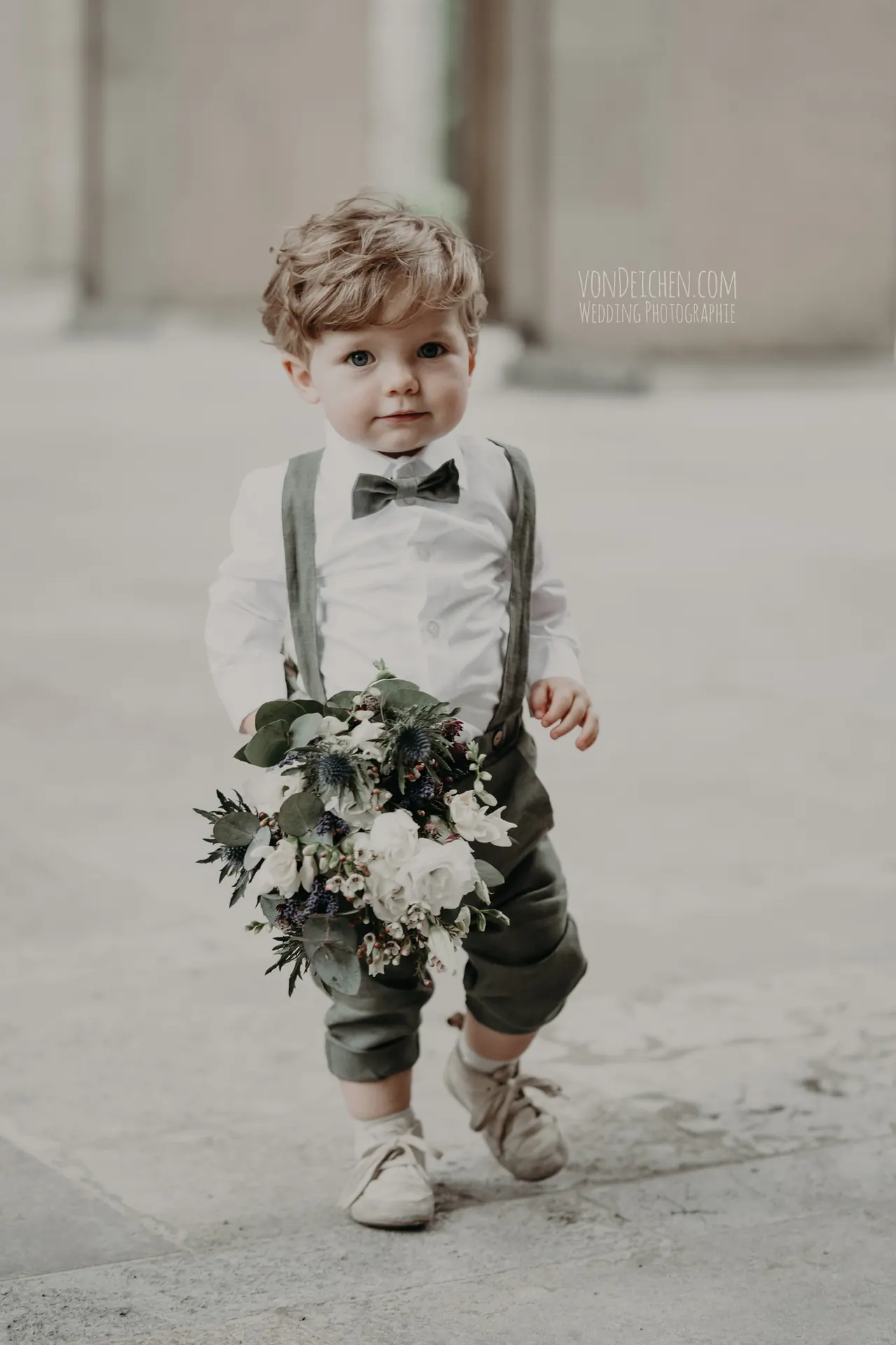 Kleiner Junge mit Hosenträgern und Blumenstrauß