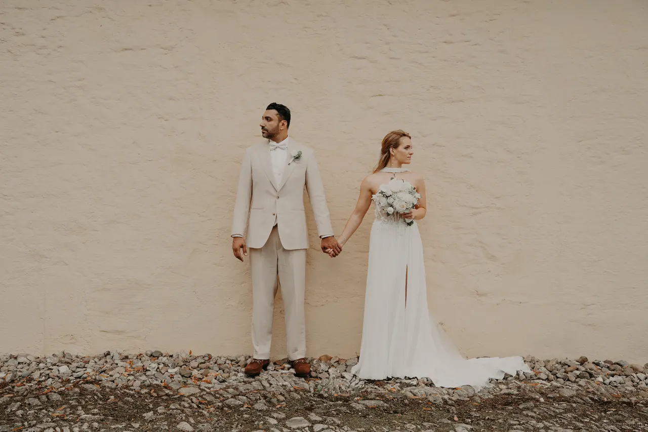 Hochzeit von Aris Foodspot aus Braunschweig: Brautpaar Hand in Hand vor einer hellen Mauer